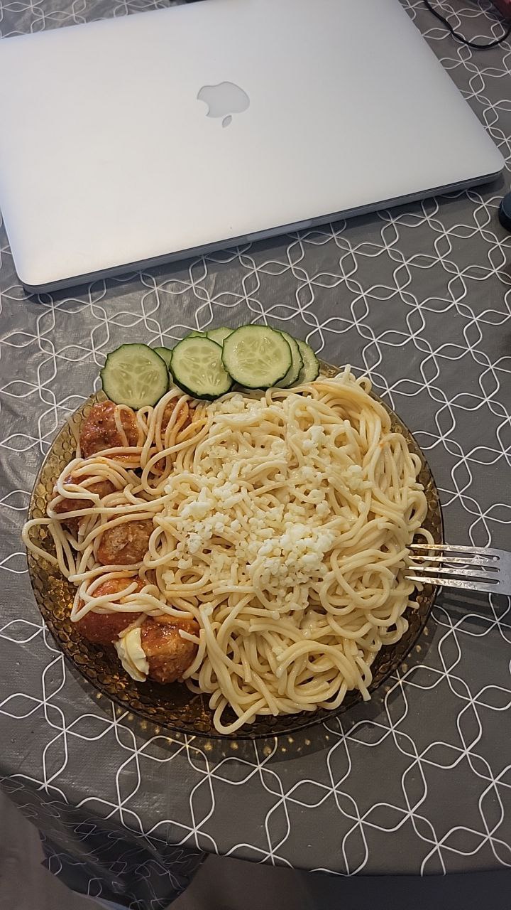 Spaghetti With Tomato Sauce And Meatballs, Garnished With Cucumber Slices And Feta Cheese