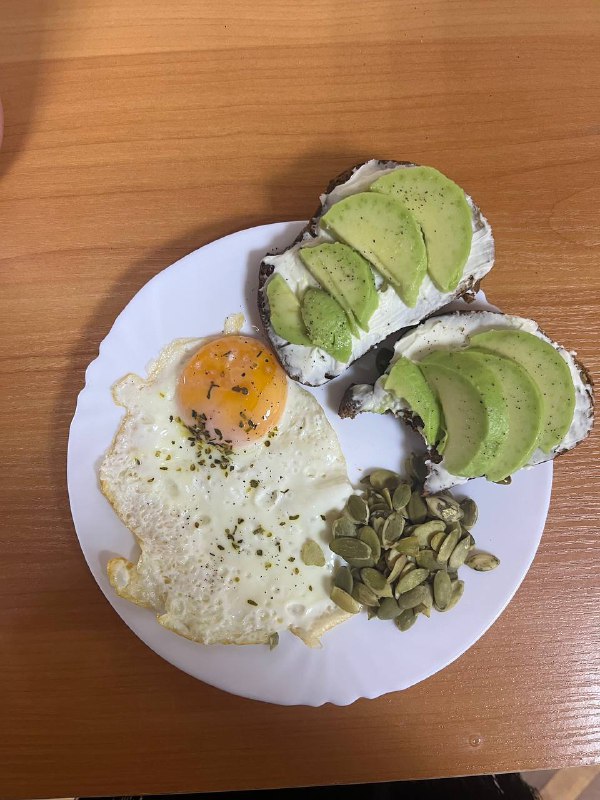 Avocado On Toast With Cream Cheese And A Fried Egg, Served With Pumpkin Seeds