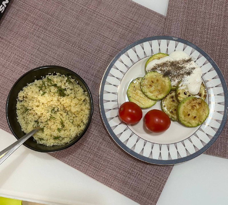 This Appears To Be A Meal Consisting Of Couscous, Grilled Zucchini, Yogurt With Herbs, And Cherry Tomatoes.