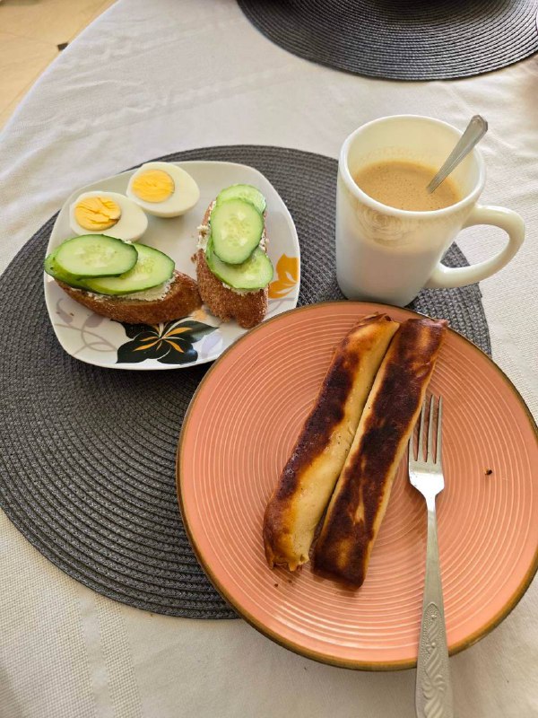 Open-faced Sandwich With Boiled Eggs And Cucumber, Rolled Pancake Filled With Cottage Cheese And Jam, And A Cup Of Coffee With Milk